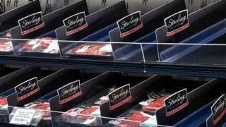 Display case of Sterling Silver Premium Meats packaging in a supermarket meat section, with red meat cuts visible in clear bins